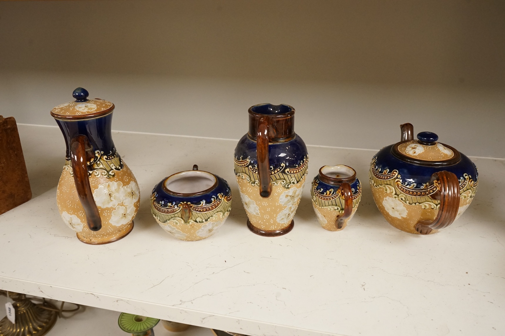 A small collection of Doulton Lambeth stoneware comprising, tea and coffee pots, two jugs and sugar bowl, largest 21cm high